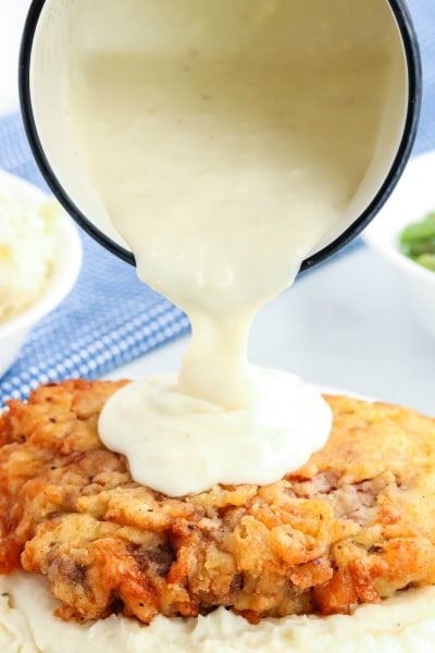 Chicken Fried Steak with White Gravy - pouring gravy over fried chicken steak