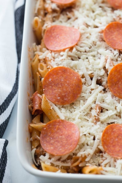 Pizza casserole topped with shredded cheese and pepperoni slices