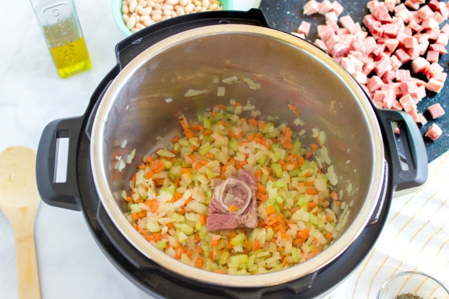 Chopped vegetables sauting in instant pot with ham bone