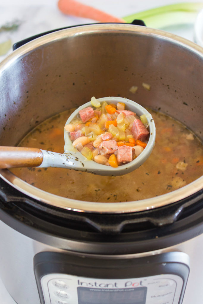 Instant Pot Ham and Bean Soup - soupin instant pot, with spoon scooping out soup