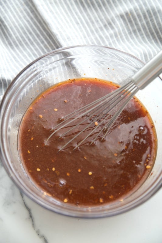 bbq root beer sauce in a glass mixing bowl with a whisk