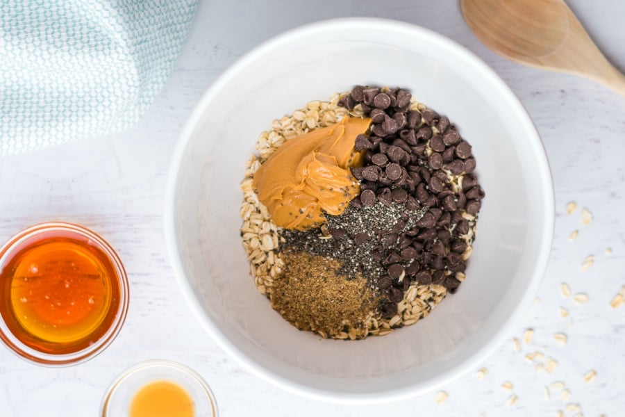 Oats, sugar, peanut butter, chia seeds, and sugar in a white mixing bowl