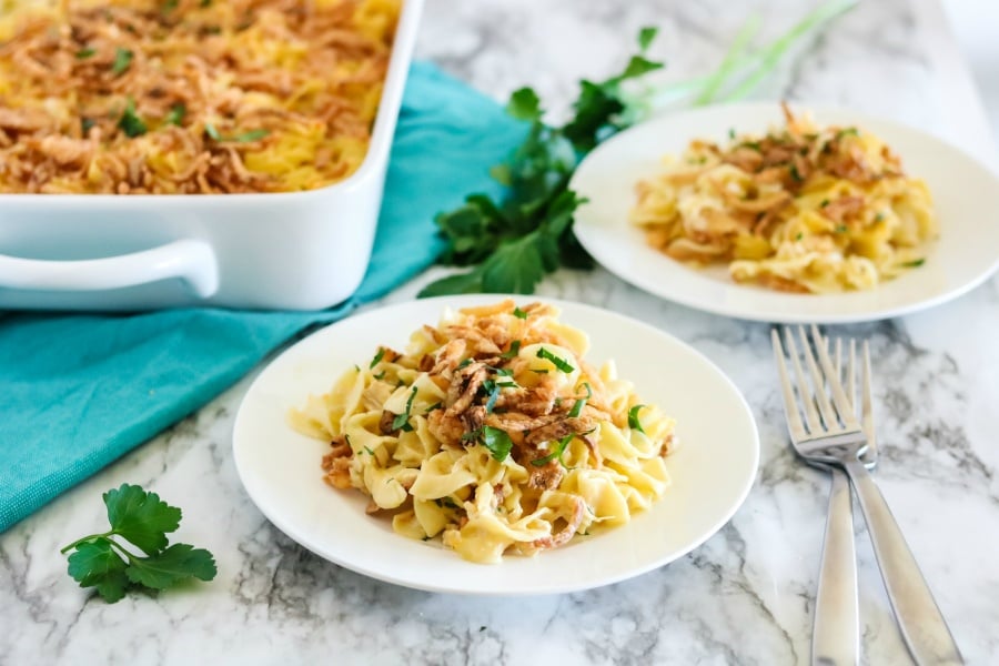 2 plates of french onion chicken noodle casserole, with casserole dish in the background