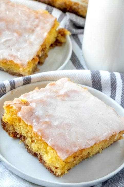 Honey Bun Cake Recipe - 2 plates with a Slice of cake on a white plate with a container of milk on the right