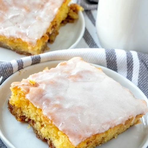 Honey Bun Cake Recipe - 2 plates with a Slice of cake on a white plate with a container of milk on the right