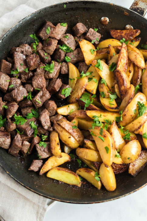 One Pot Steak and Potato Bites in a frying pan and topped with parsley