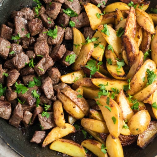 One Pot Steak and Potato Bites in a frying pan and topped with parsley