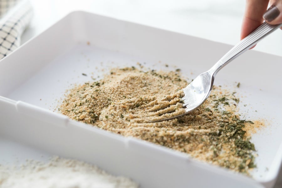 mixing together parmesan cheese, seasoning and bread crumbs with a fork