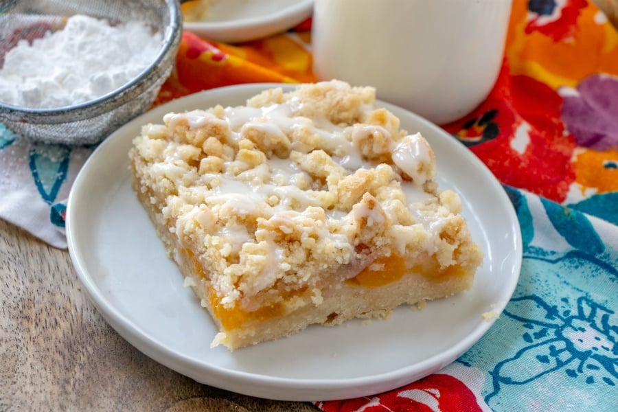 piece of peach crumble bar on a white plate