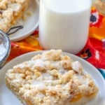Peach Crumble Bars - piece of peach cumble bar on a white plate with jug of milk in background