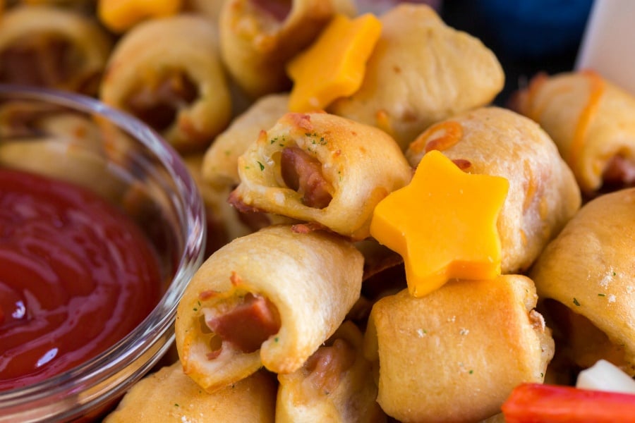 close up image of mini hotdog nuggets, topped with cheddar cheese stars - on the 4th of July Snack Board