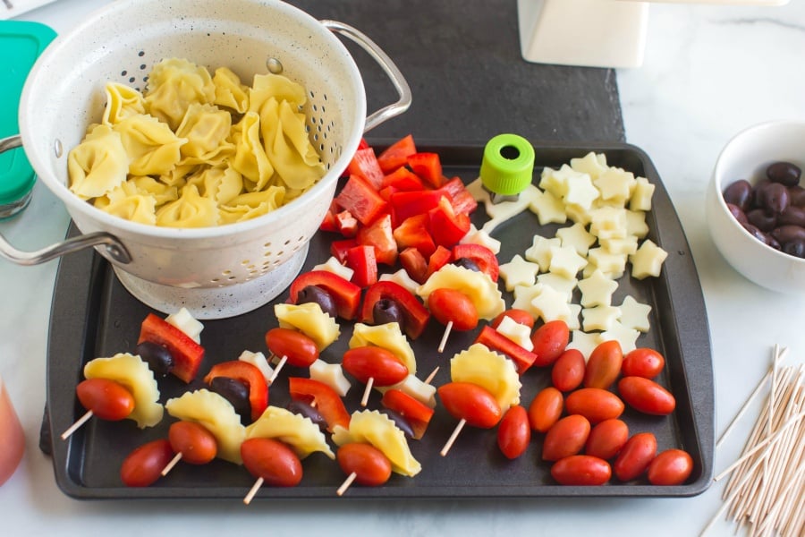 pasta, olives and cheese stars on a baking sheet, being made into kabobs