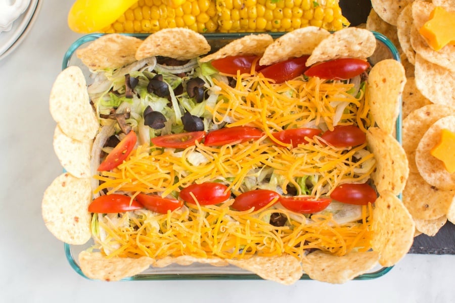 small taco salad with shredded cheese, tomatoes, lettuce, and chips, laid out to look like an American Flag, set on the 4th of July Snack Board