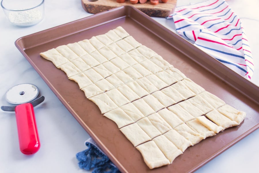 crescent dough on baking sheet cut into small squares with pizza cutter