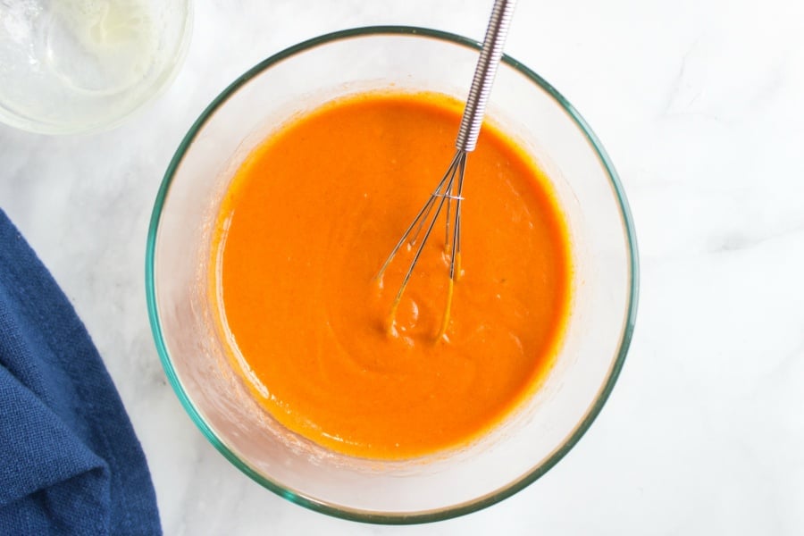 buffalo wing sauce in a mixing bowl with whisk