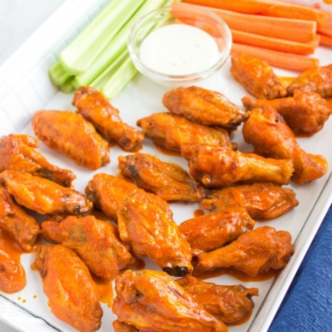 buffalo wings, celery and carrot sticks on a serving platter, with s dipping cup of dressing