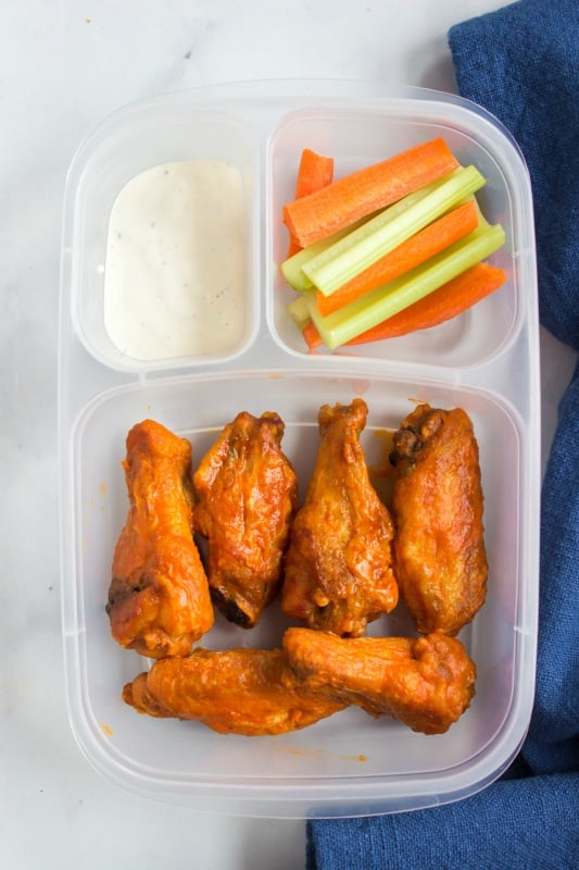 leftover wing in a lunchbox with a side of celery and carrots