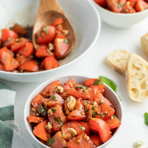 Balsamic Tomato Salad recipe served in a two small white bowl with a side of french bread