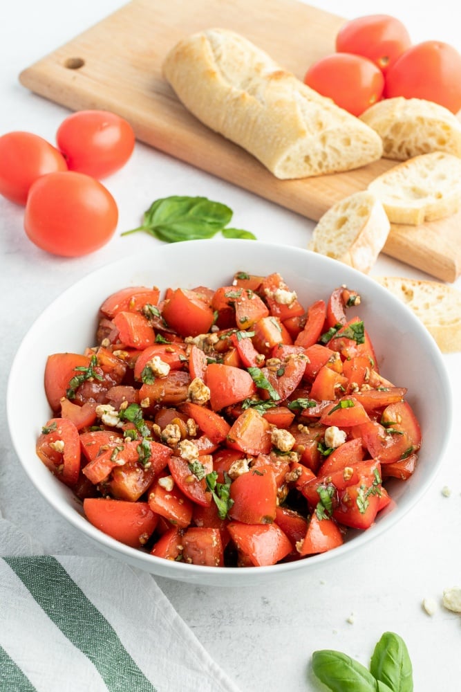 Balsamic Tomato Salad recipe served in a white bowl with a side of french bread