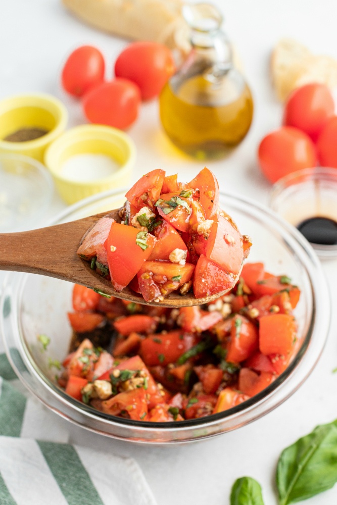 Tomato salad being scooped up with a wooden spoon.