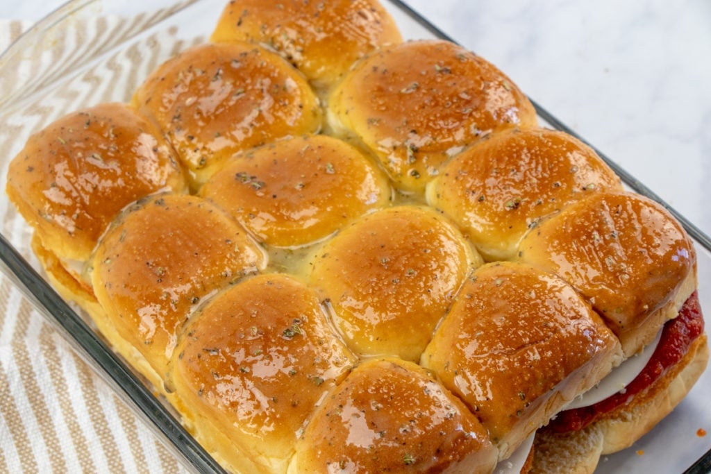 sliders in a baking sheet with butter mixture brushed on top