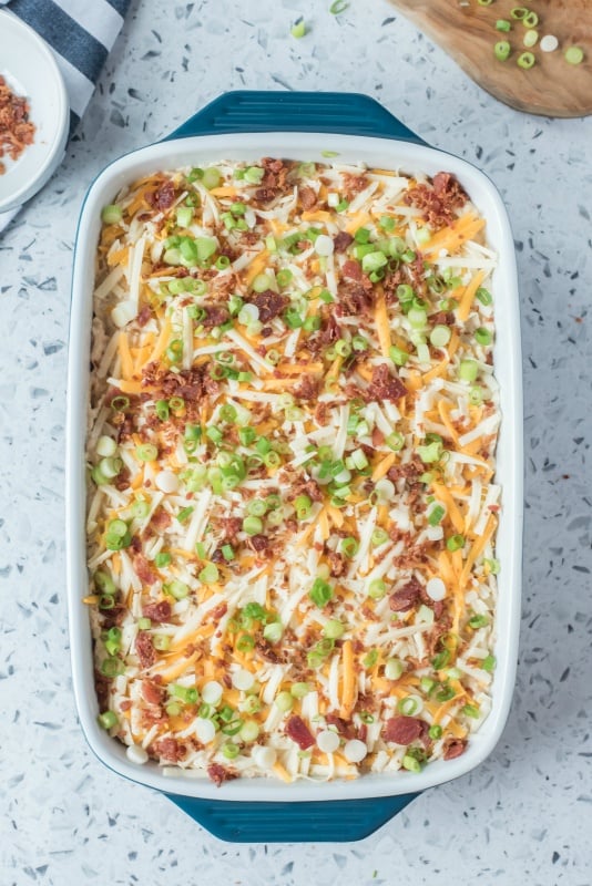 Shredded cheese, bacon and chives on top of chicken lasagna