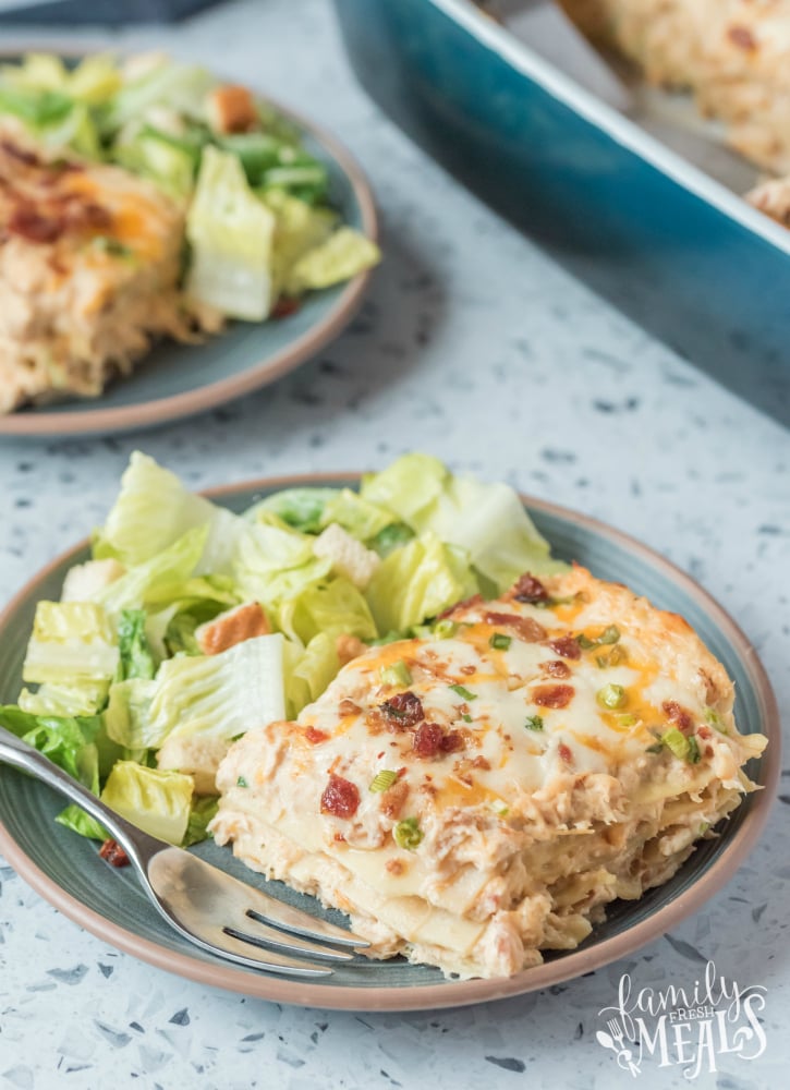 Two plates with a slice of crack chicken lasagna and salad