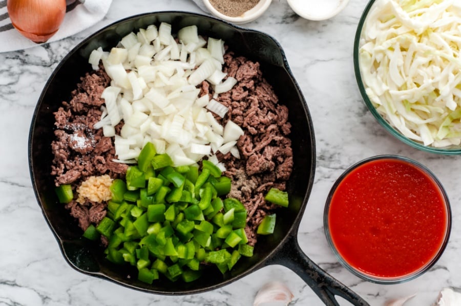 Cooked ground beef, onions, bell peppers and garlic in a cast iron pan