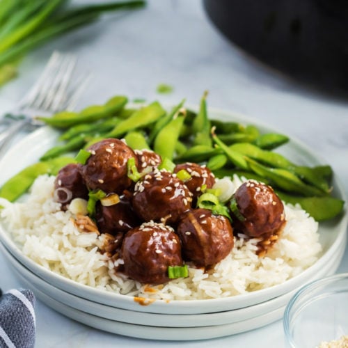 Crockpot Teriyaki Meatballs served over rice on a white plate, with a side of edamame