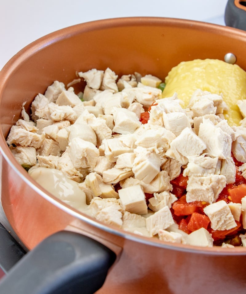 chicken and creamed soups being added to cooking pan with onions and peppers