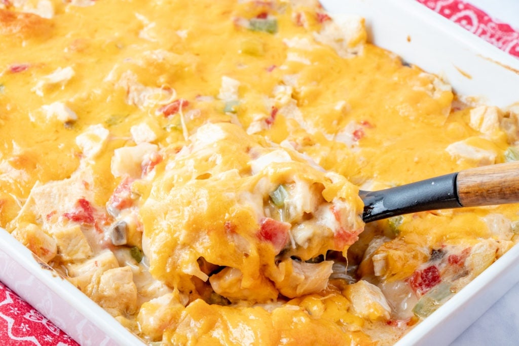 King Ranch Chicken Casserole in a baking dish, being scooped up with a serving spoon