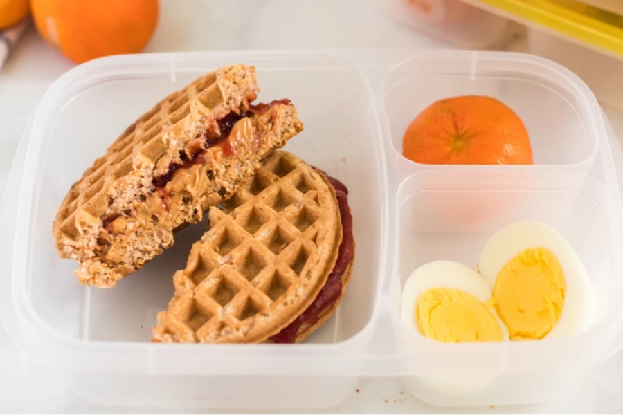 PBJ Waffle Sandwich packed in lunchbox with an orange and hard boiled egg