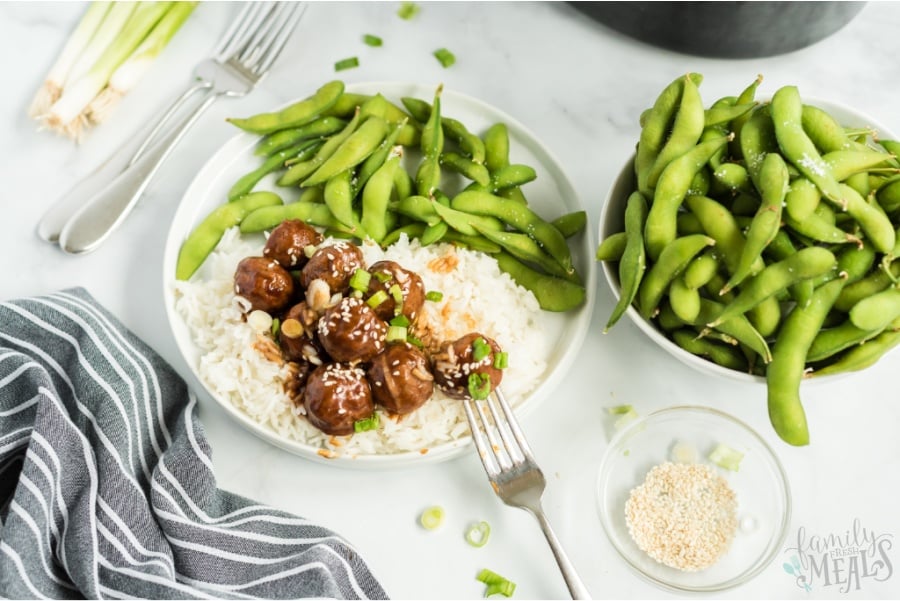 Teriyaki Meatballs served over rice on a white plate, with a side of edamame