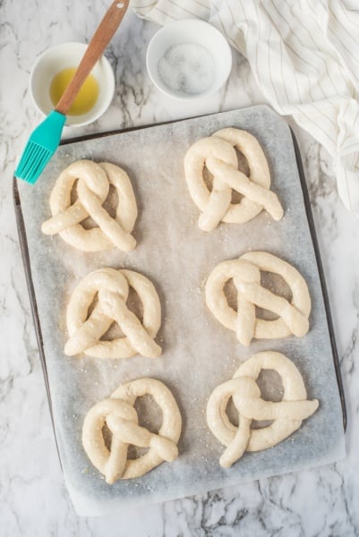 dough shaped into pretzel shape, on a baking sheet
