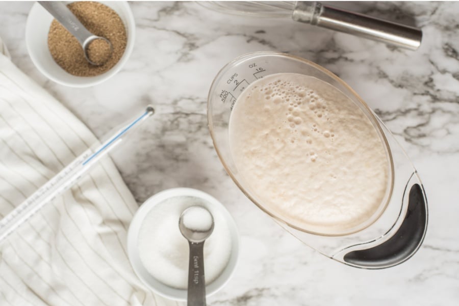 frothy mixture in a measuring bowl and a small container of salt and yeast