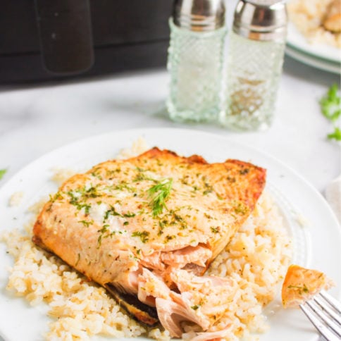 piece of air fryer salmon on a bed of rice - served on a white plate