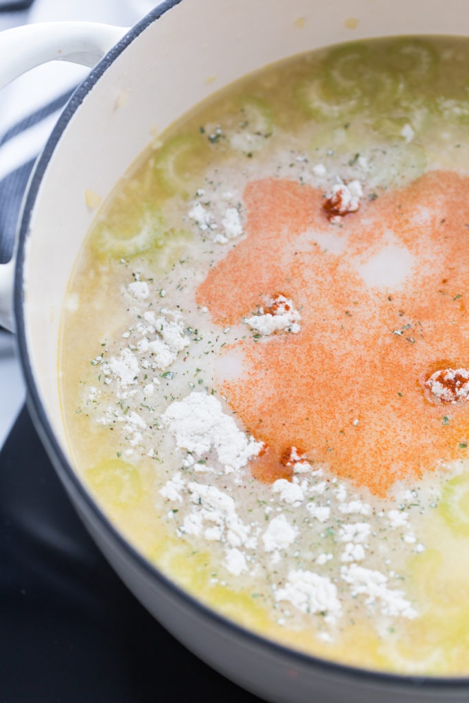 Chicken, condensed soup, chicken stock, water, milk, cream cheese, ranch dressing mix, and smoked paprika being added to the soup pot