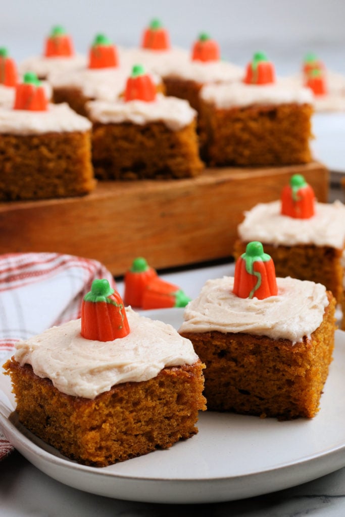 several pumpkin bars on a plate and on a wooden board