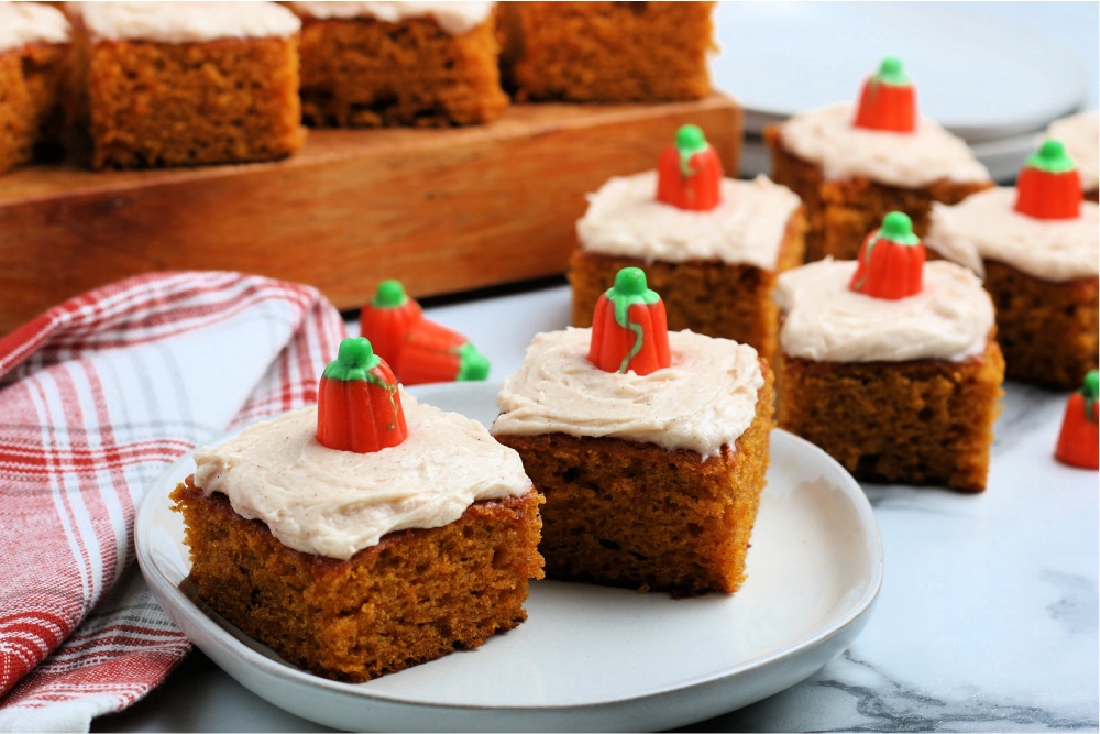 several pumpkin bars on a plate and on a wooden board