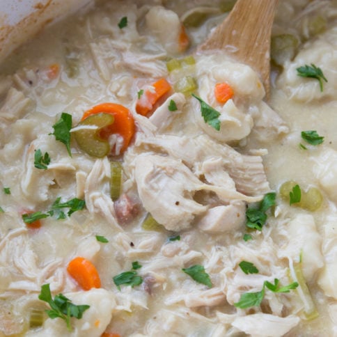 Chicken and Dumplings in a slow cooker with a wooden spoon