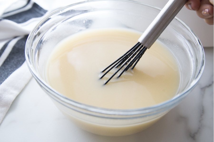 a creamy sauce in a mixing bowl with a whisk