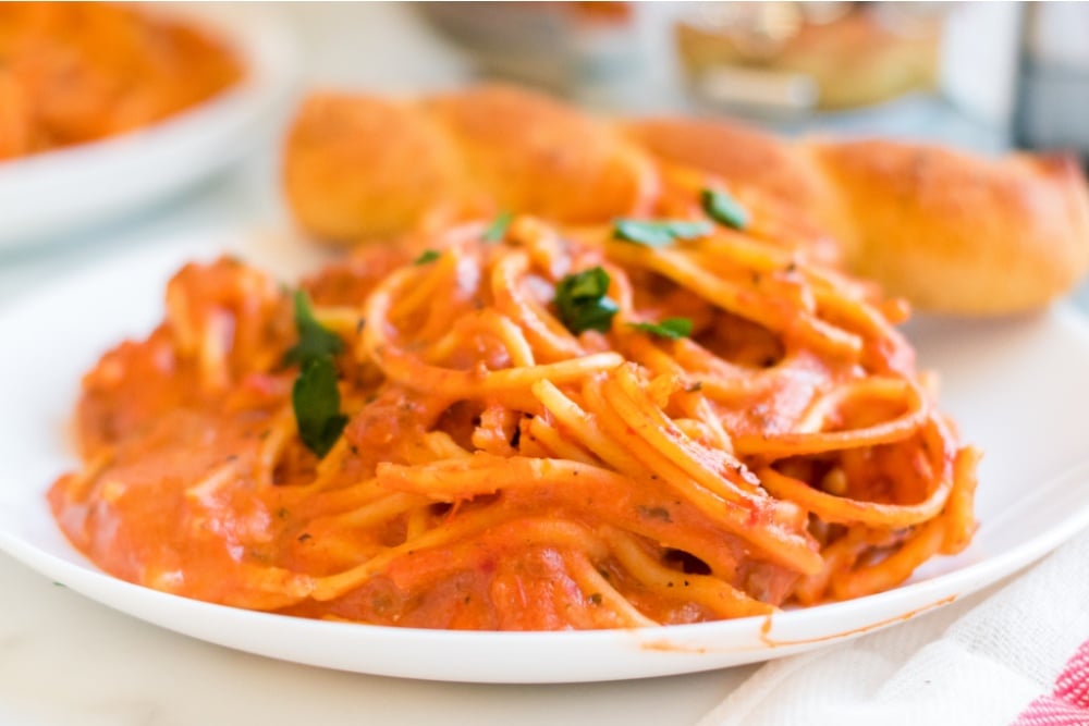 Creamy Crockpot Spaghetti on a plate with a bread stick