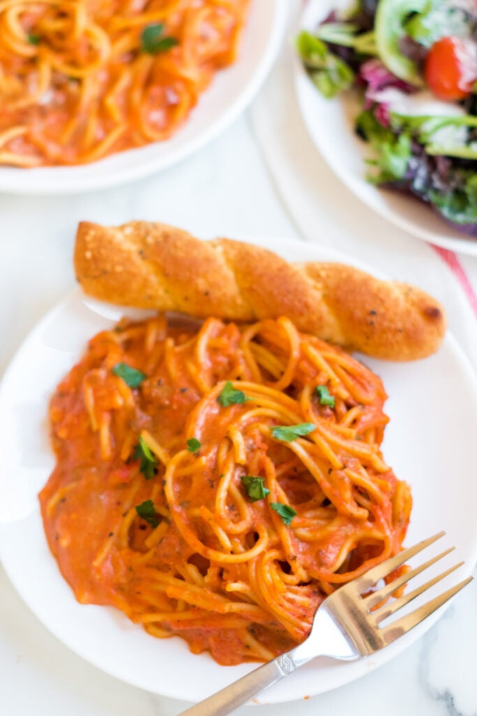 Creamy Crockpot Spaghetti on a plate with a bread stick