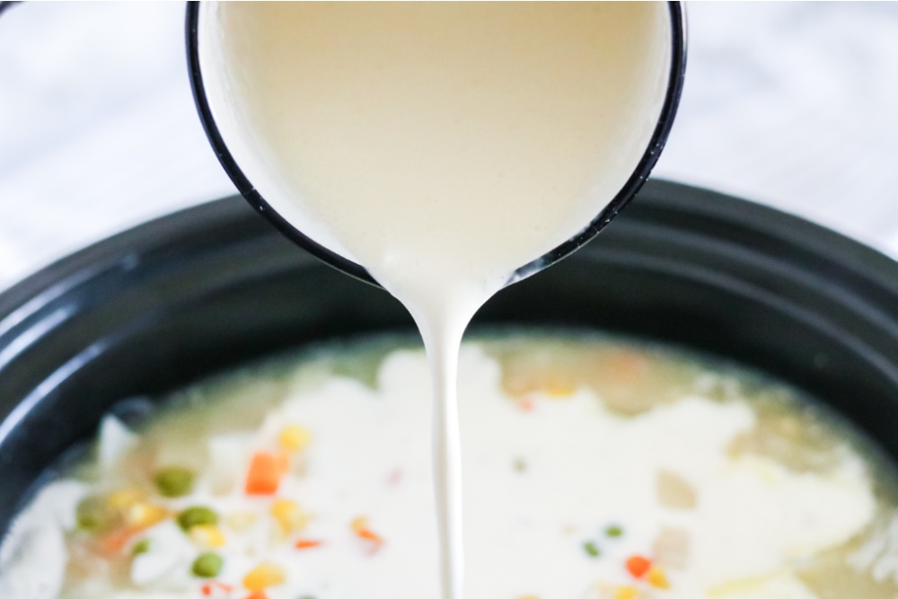 pouring creamy mixture into the slow cooker