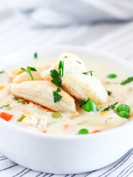Crockpot Chicken Pot Pie Soup in a white bowl - with puff pasty triangles on top