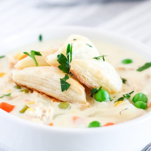 Crockpot Chicken Pot Pie Soup in a white bowl - with puff pasty triangles on top