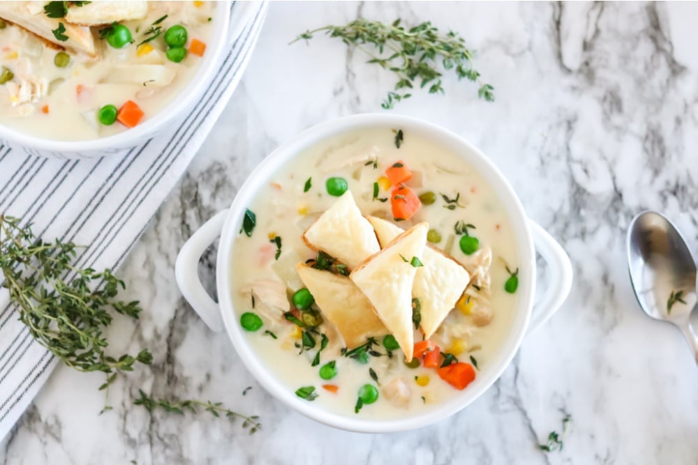 Crockpot Chicken Pot Pie Soup in a white bowl - with puff pasty triangles on top