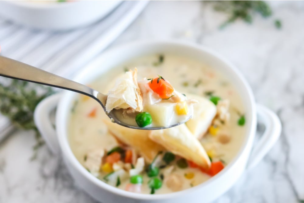 Crockpot Chicken Pot Pie Soup in a white bowl with a spoon scooping some up