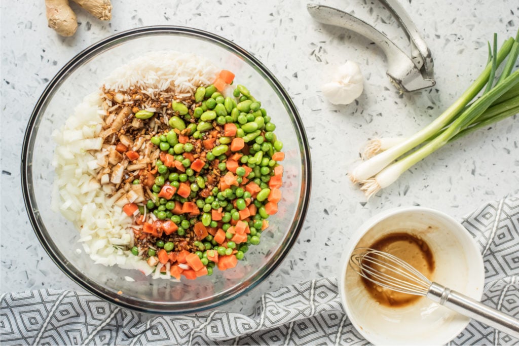Rice in a large bowl and add diced onion, peas and corn, edamame beans, and soy sauce mixture.