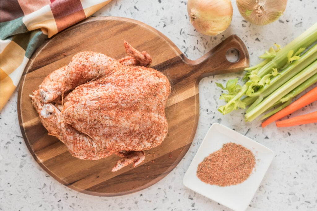 Chicken with seasonings, on a cutting board 